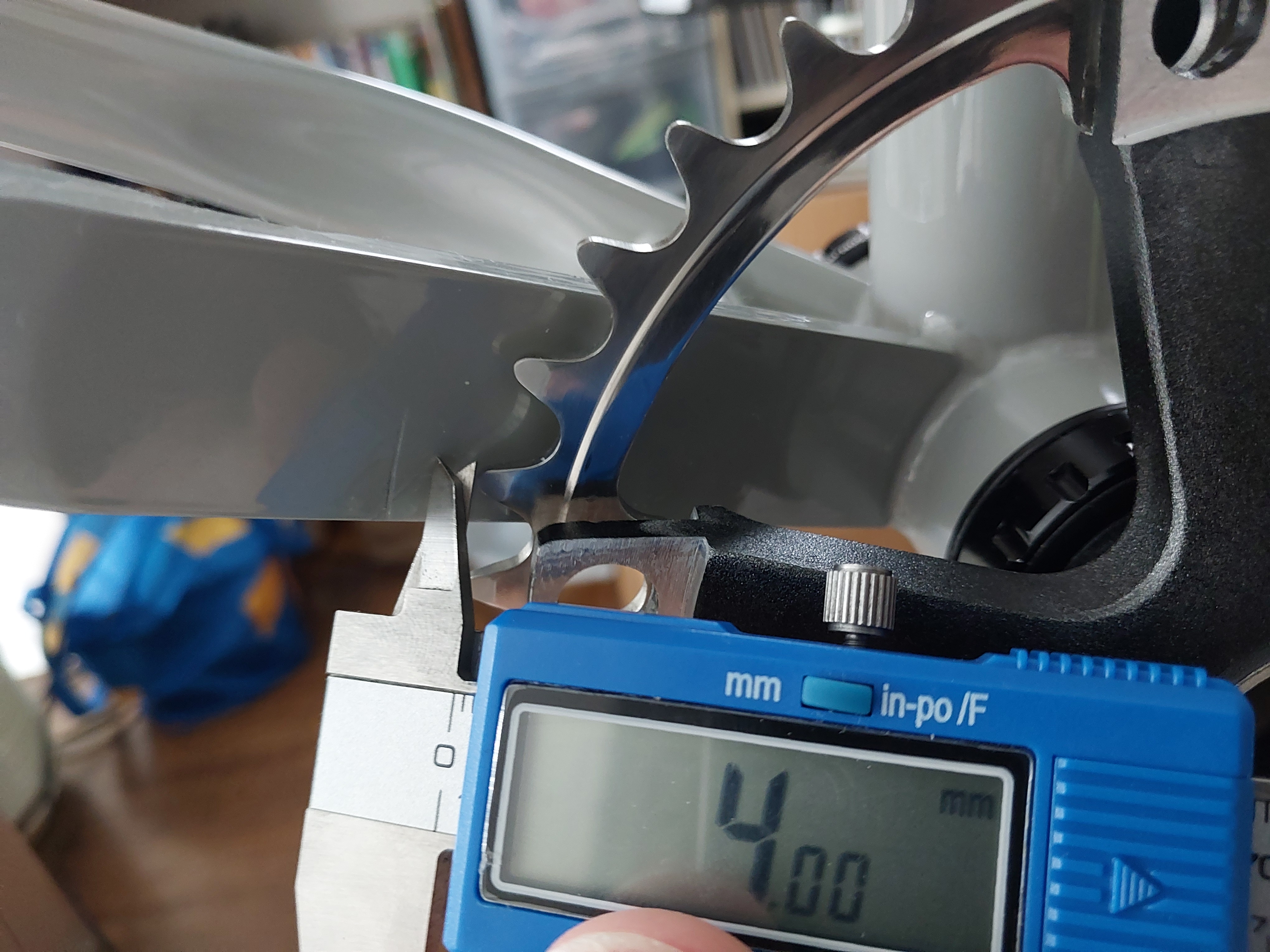 Chainring on bicycle with calipers showing 4 mm clearance between chainstay and chainring